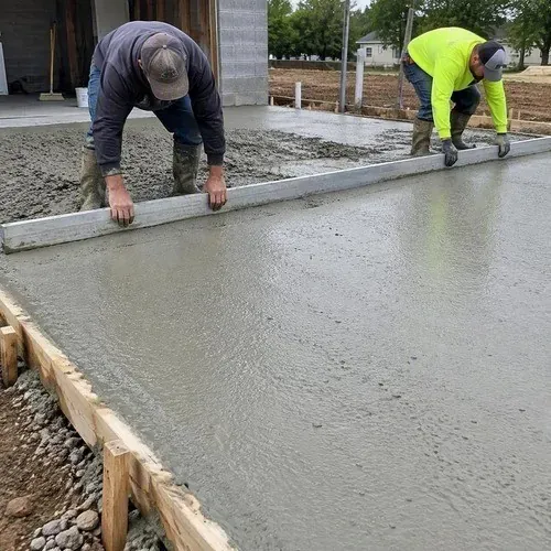 Wet concrete being screeded flat with a long straightedge
