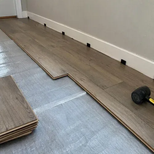 Laminate planks click-locked with spacers holding the expansion gap at the wall