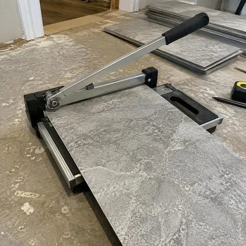 Stone-look luxury vinyl tile being cut on a vinyl tile cutter