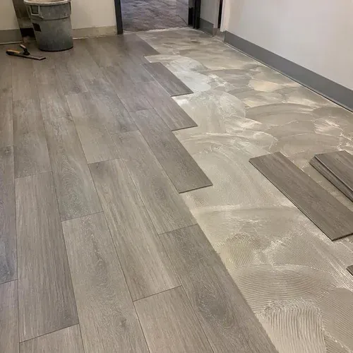 Luxury vinyl tiles set into adhesive in a staggered pattern