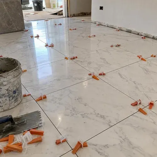 Levelling clips and wedges across freshly set marble tile