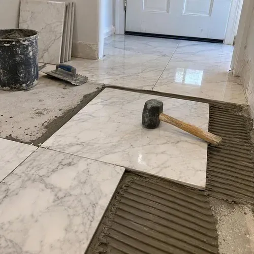 White marble tiles set into white thinset with a rubber mallet
