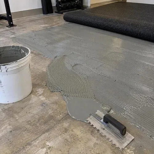 Urethane adhesive troweled on concrete before a rubber floor sheet is laid