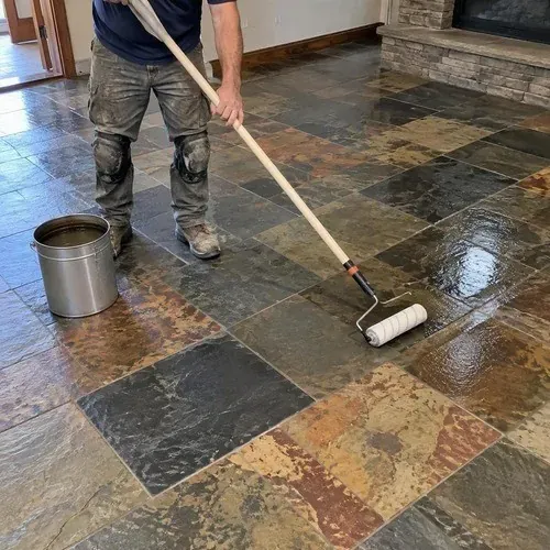 Installer sealing a finished slate floor with a pole roller