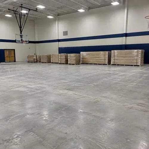 Pallets of maple strip sports flooring on a gym slab before installation
